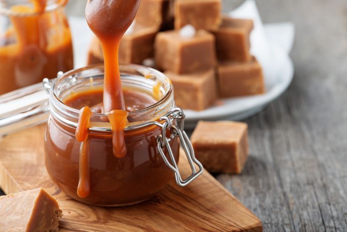 Dairy free caramel sauce in a jar with fudge in the background