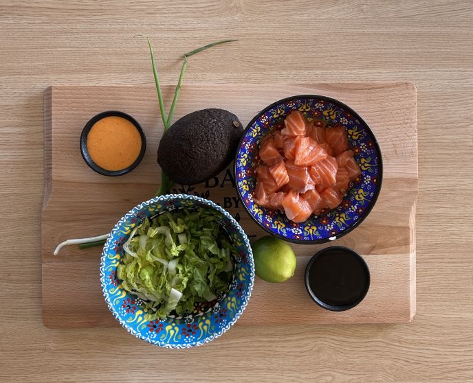 Salmon tacos ingredients: sriracha mayo, spring onions, lettuce, avocado, salmon, lime, and teriyaki sauce