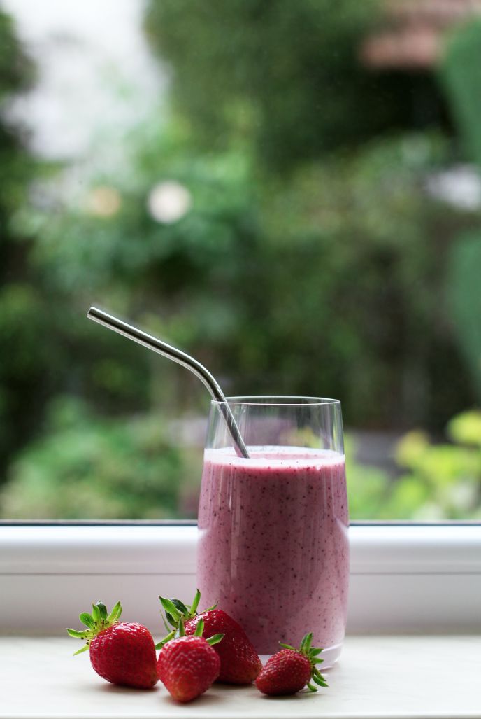 Strawberry smoothie by a window with fresh fruits
